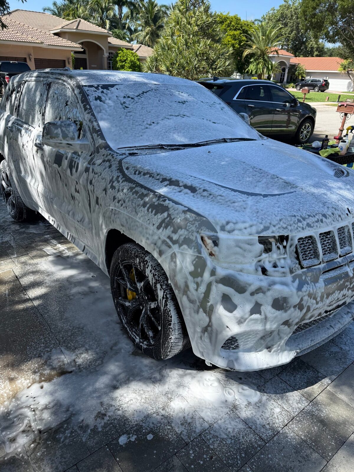 A vehicle covered in thick snow-foam during a premium hand wash